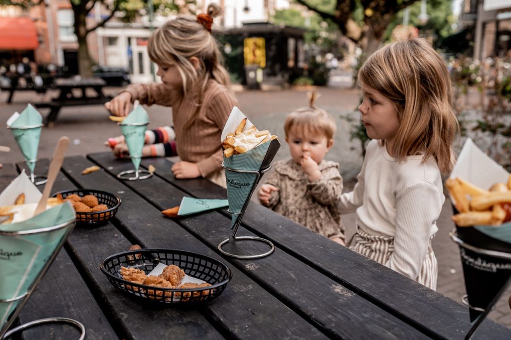Kinderen aan de picknicktafel met friet en snacks