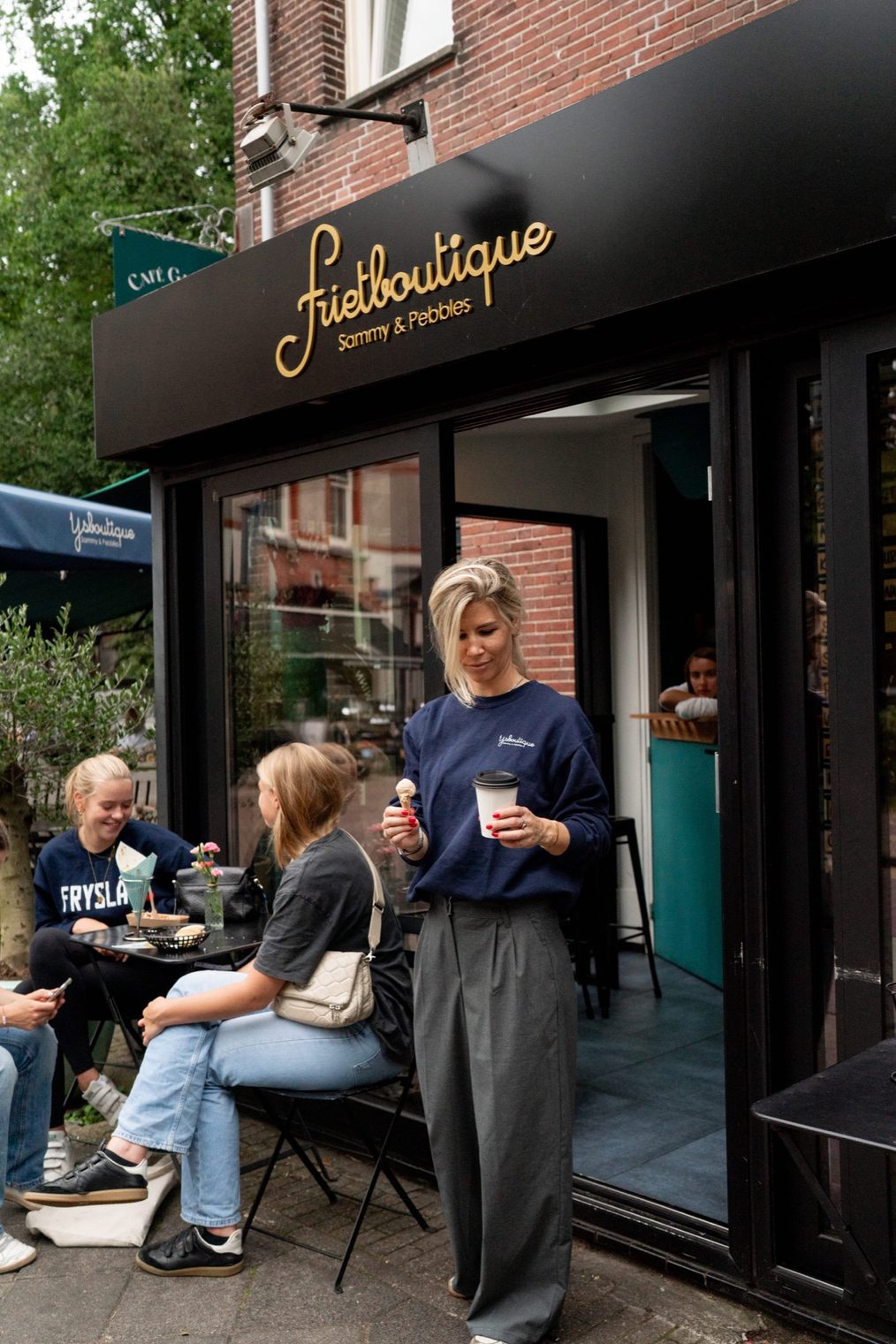Gevel met het gouden Frietboutique-logo en terras